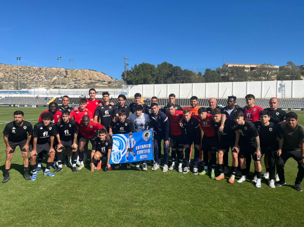 Jugadores y cuerpo técnico del Hércules B posan con una pancarta en apoyo a Adrián Jiménez, operado recientemente de una grave lesión